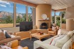 The living area has a wood burning fireplace, flat screen TV and panoramic red rock views
